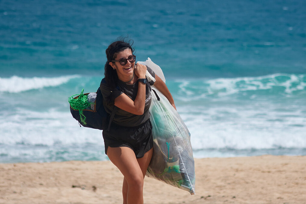 A person on the beach with a bag of litter she picked up